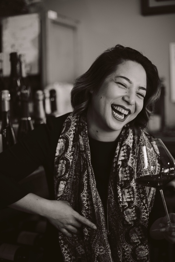 Black and white image of woman holding wine glass and laughing