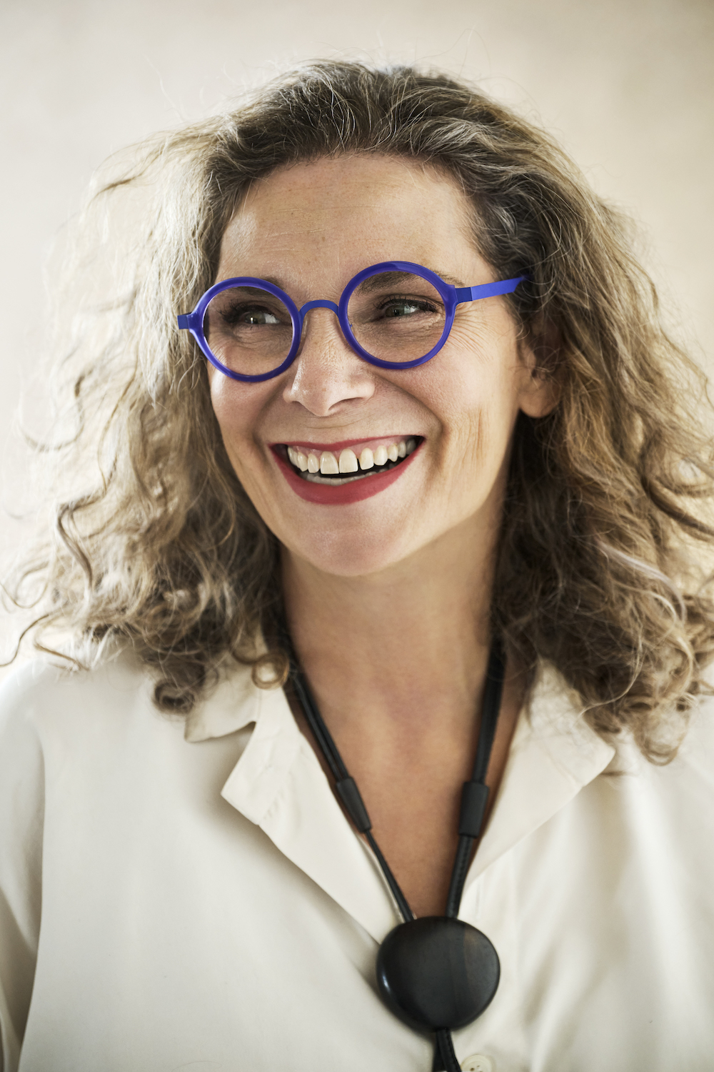 woman with blue glasses looks away from camera and smiles