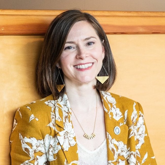 Woman in yellow jacket smiles at camera