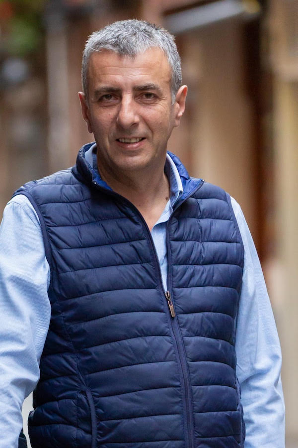 Man in blue shirt and vest facing camera