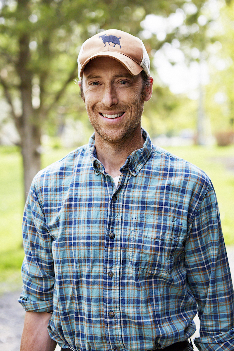 Man in plaid shirt and hat smiling