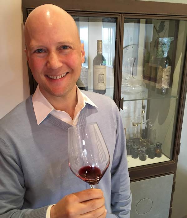 Man in blue sweater holds glass of red wine