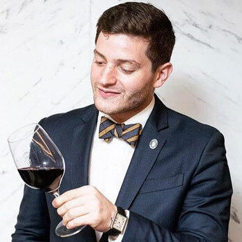 Man in suit with bow tie holding wine glass
