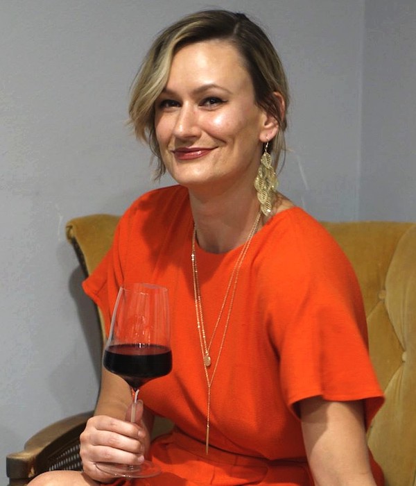 Woman in orange dress holds glass of red wine