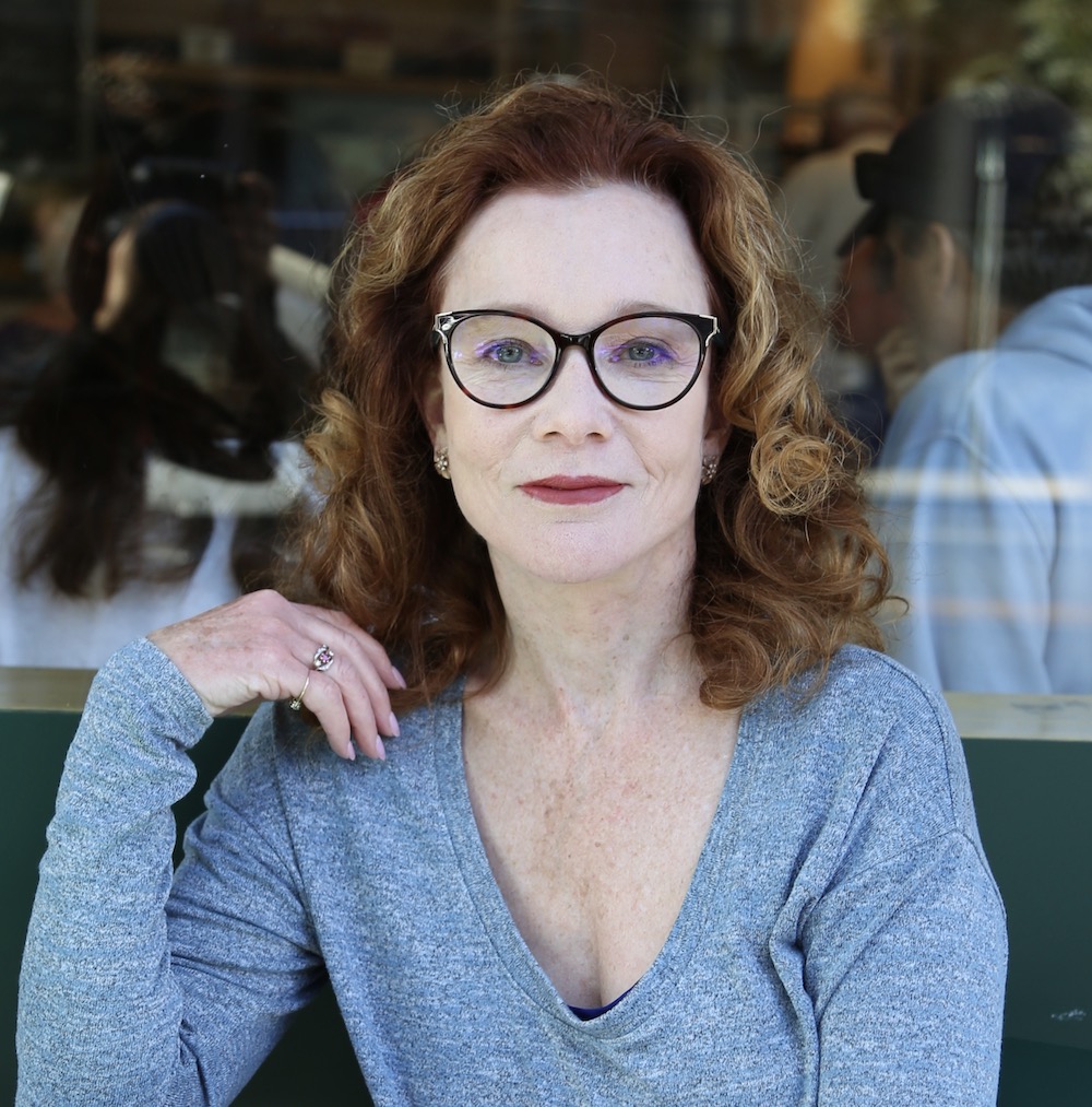 Woman in blue shirt looks directly at the camera