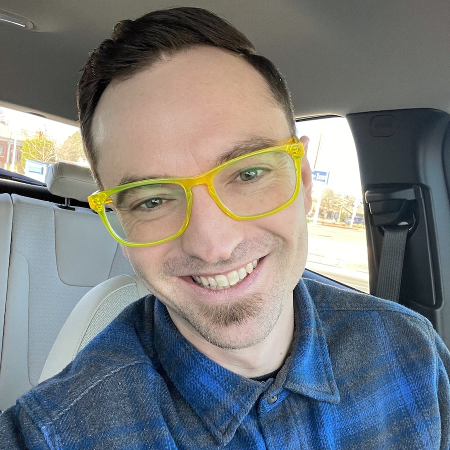 Man in bright yellow glasses looks at the camera
