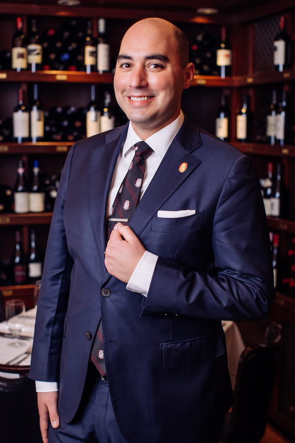 Man in dark suit smiles while looking at the camera