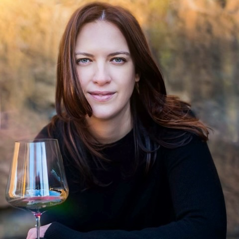 Woman holding wine glass looks at camera
