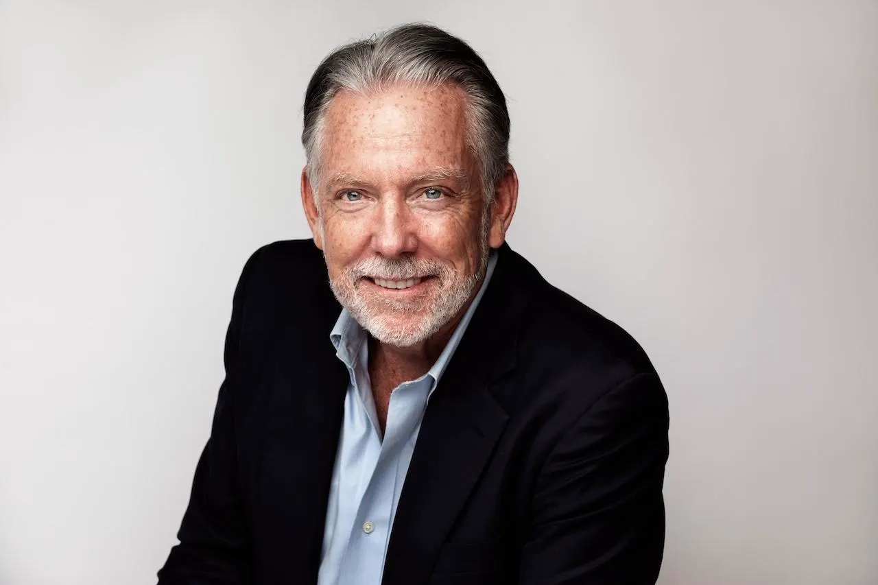 man in suit jacket looks at camera and smiles