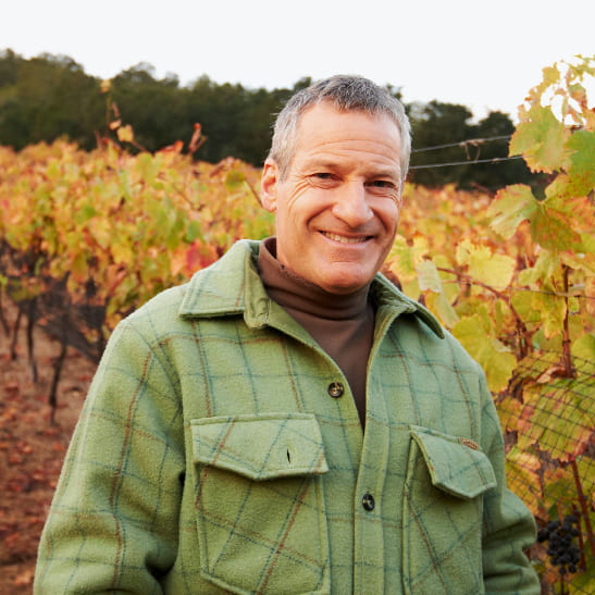 Man standing in vineyard looks at camera