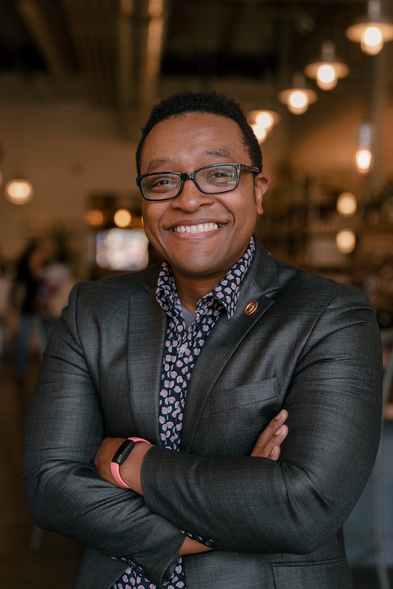 Man in dark suit looks at the camera and smiles