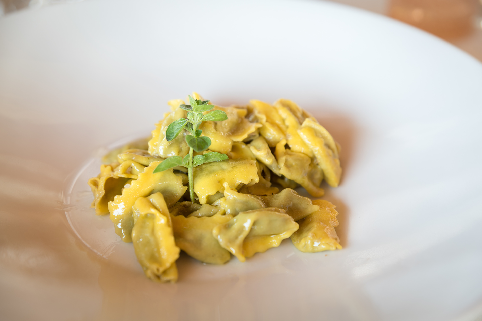 Small pockets of yellow-hued pasta in a white bowl