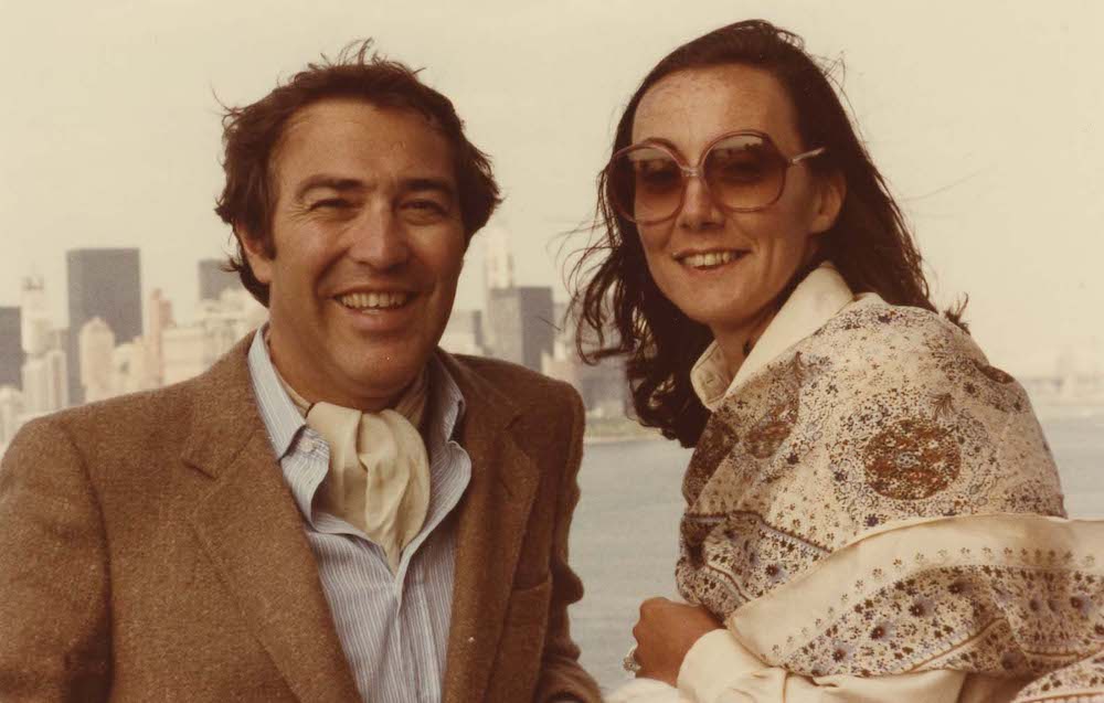 Man and woman look toward camera with New York skyline in the background