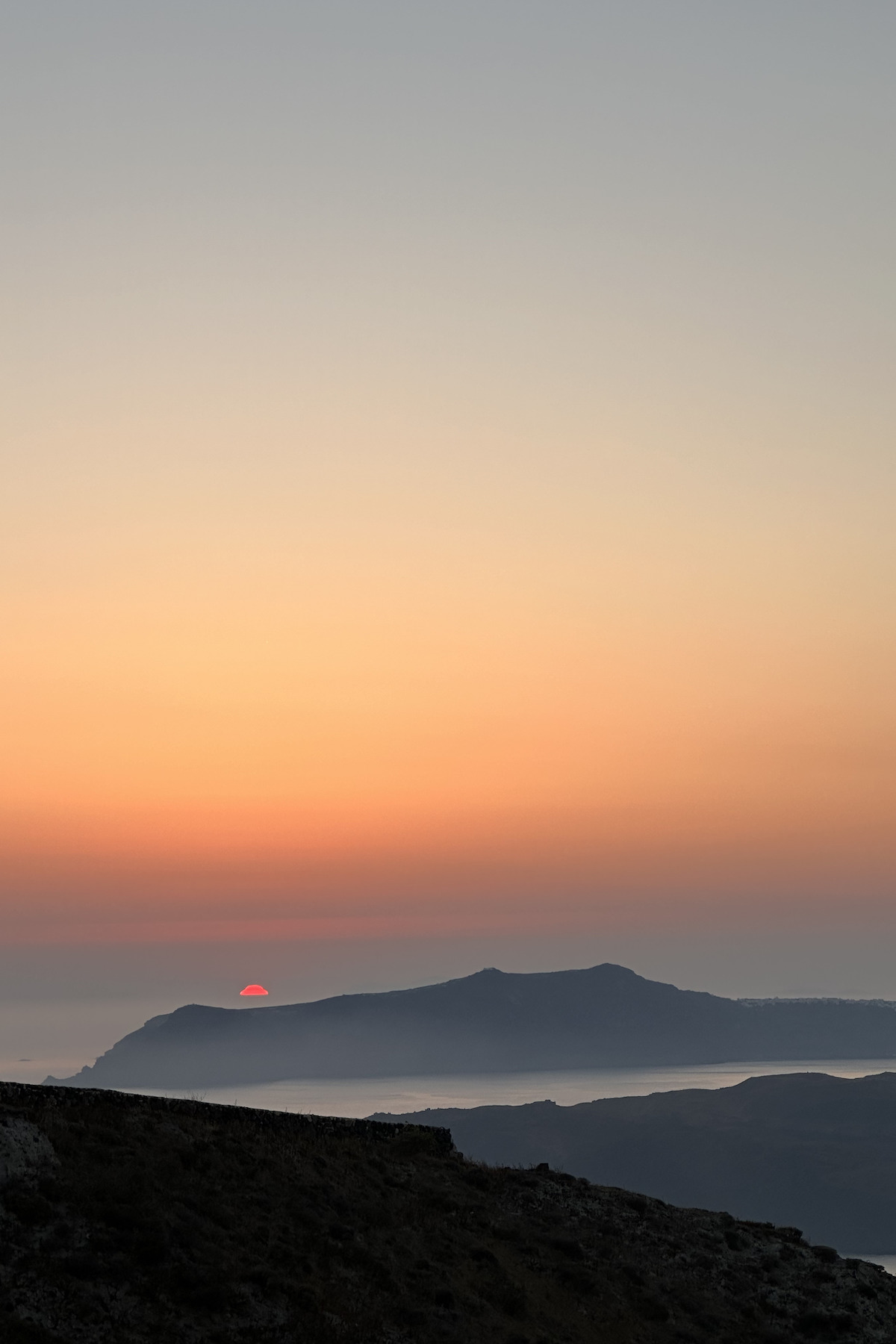 Sunset over the water with hills in the foreground