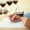 hand holding glass of red wine and writing on paper
