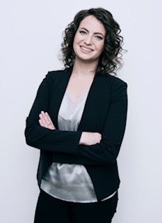 Woman in black suit looks at camera and smiles